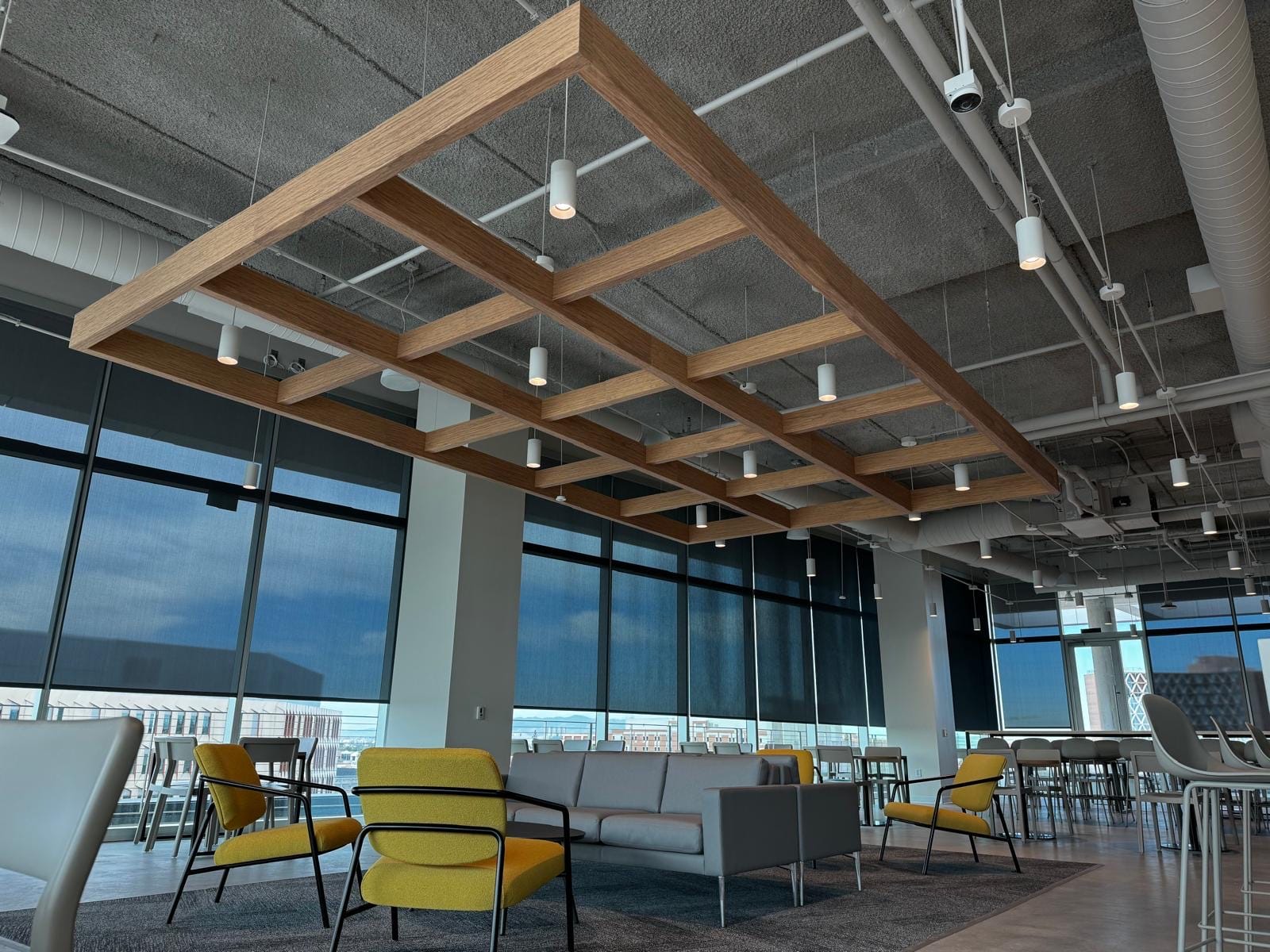 Wood-grid acoustic cloud over an office lounge with city views